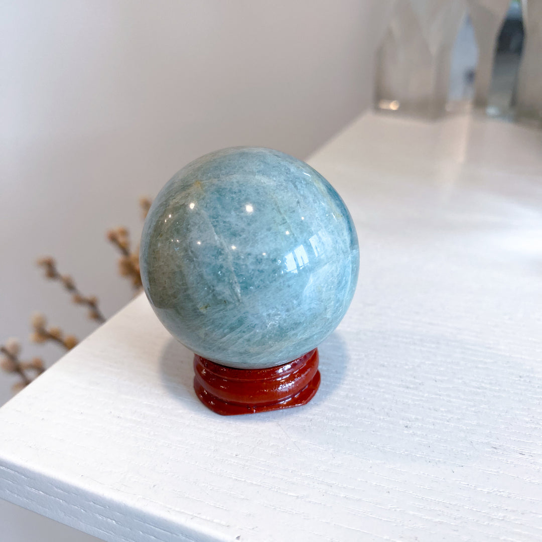 Blue crystal sphere on a red stand against a white background