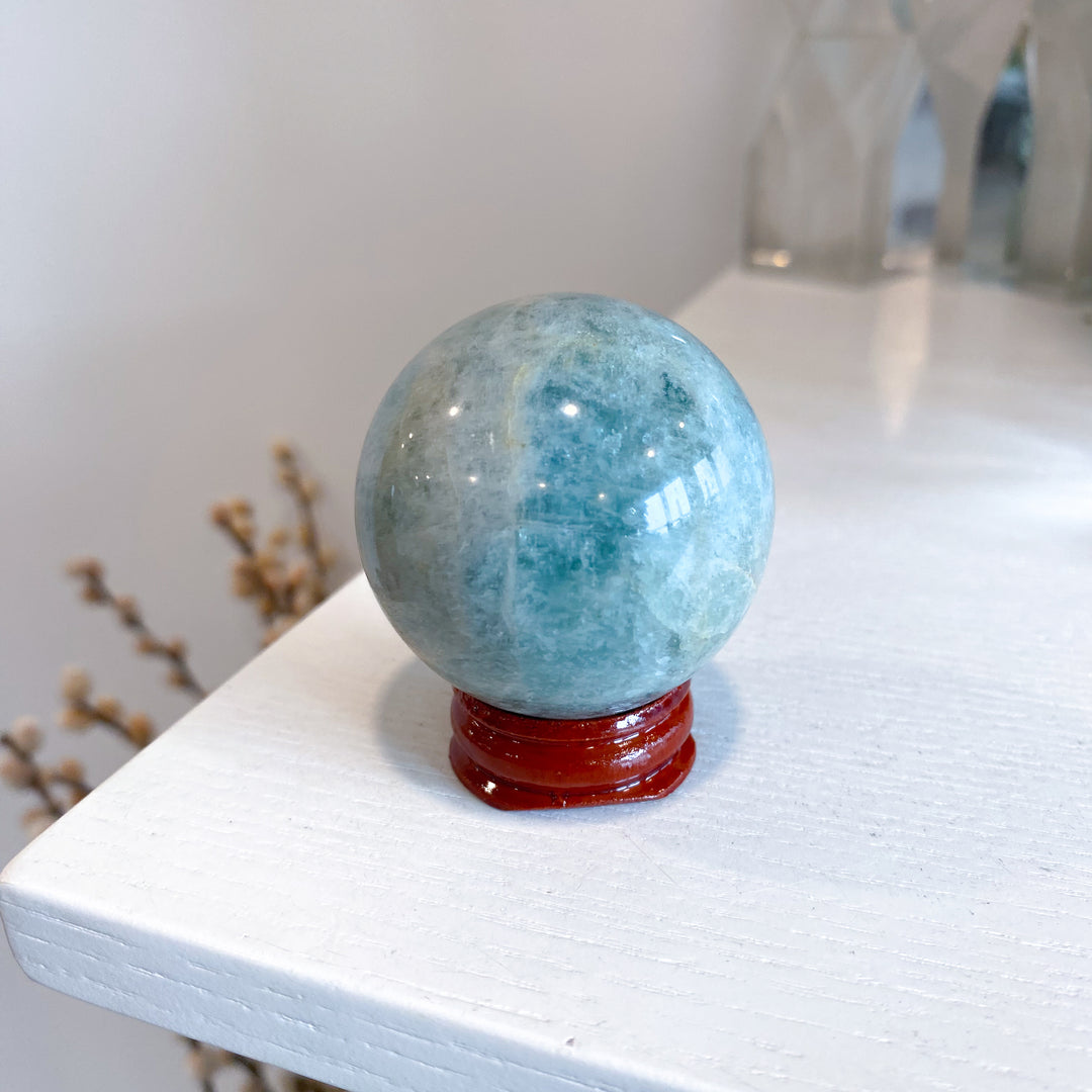 Blue crystal ball on a red stand on a white surface with a blurred background