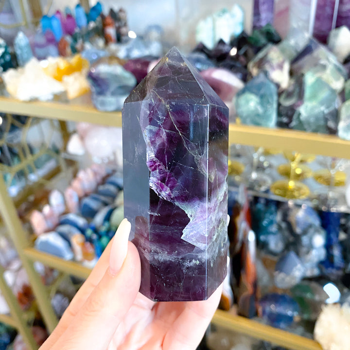 Amethyst crystal held in a hand with a blurred background of crystals and lights