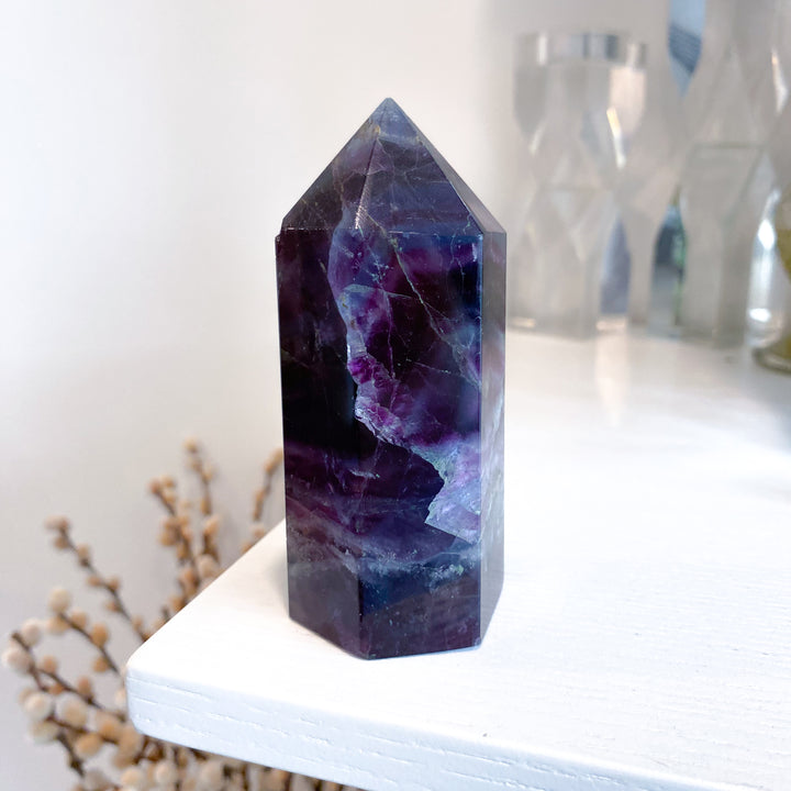 Purple crystal tower on a white surface with a blurred background