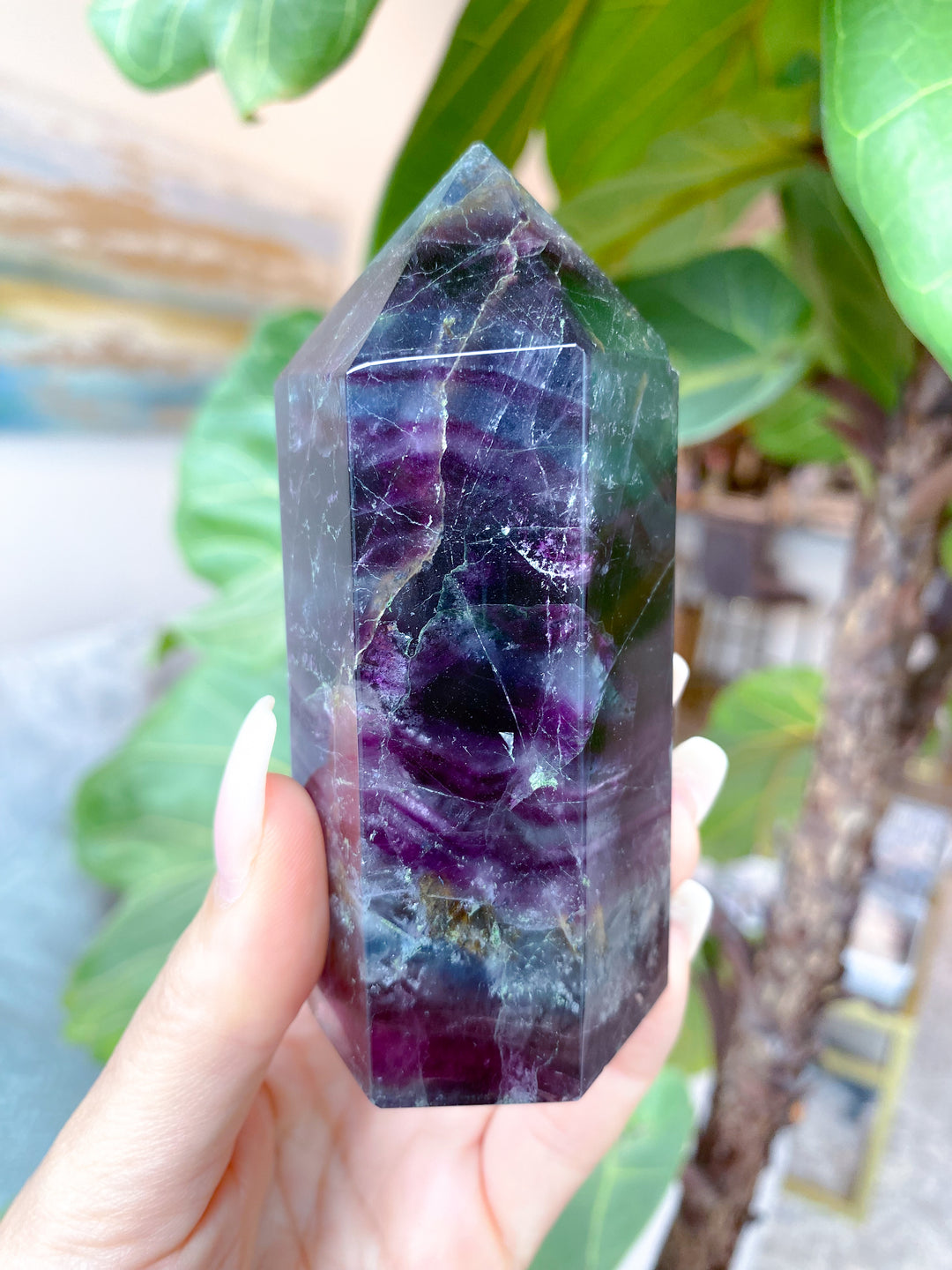 Multicolored crystal held by a hand with a blurred natural background