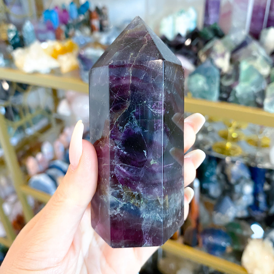 Person holding a purple crystal in front of a store display with various crystals.