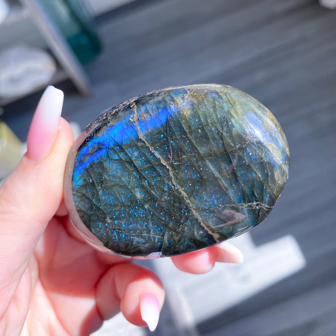 Hand holding a labradorite stone with a blurred background