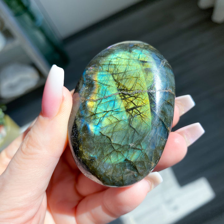 Hand holding a labradorite stone with colorful patterns