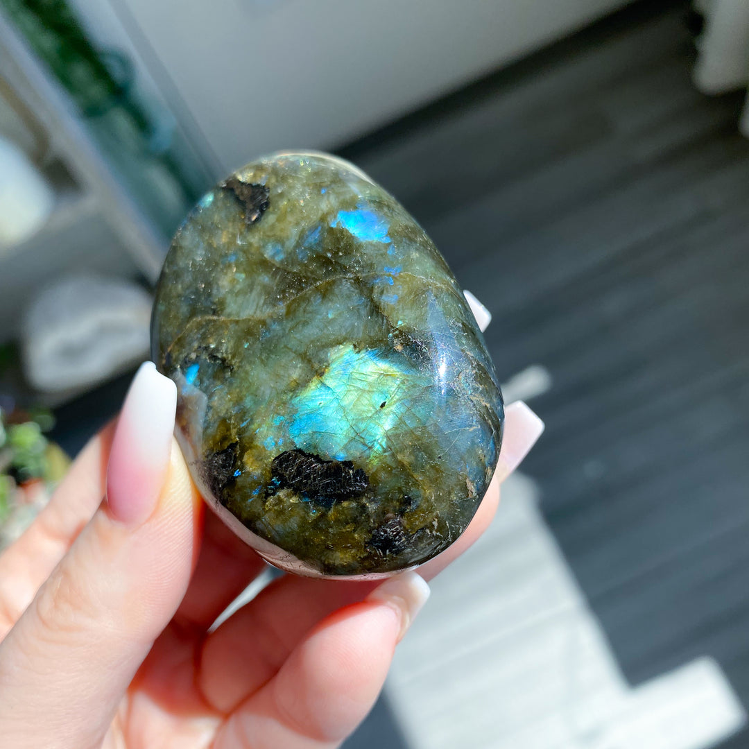 Hand holding a labradorite stone with a blurred background