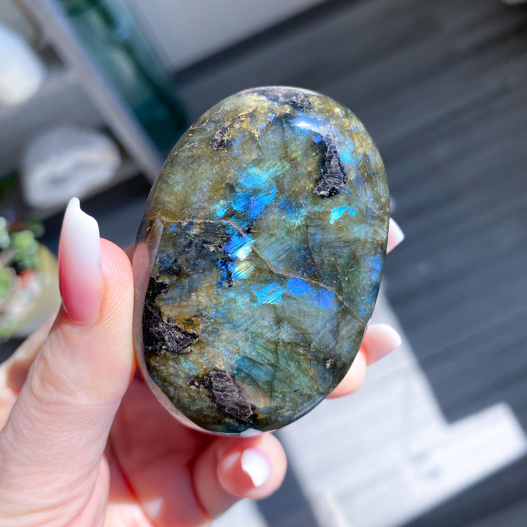 Hand holding a labradorite stone with colorful patterns