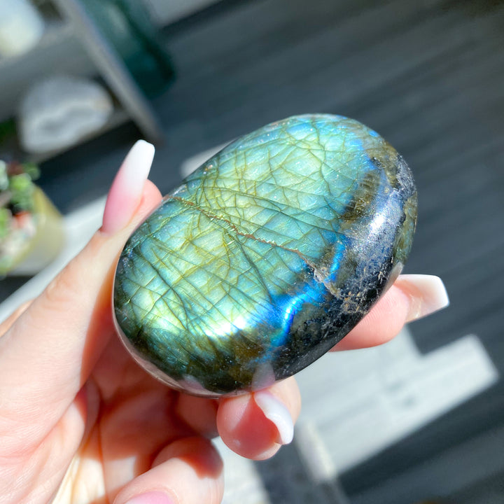 Hand holding a labradorite stone with a blurred background