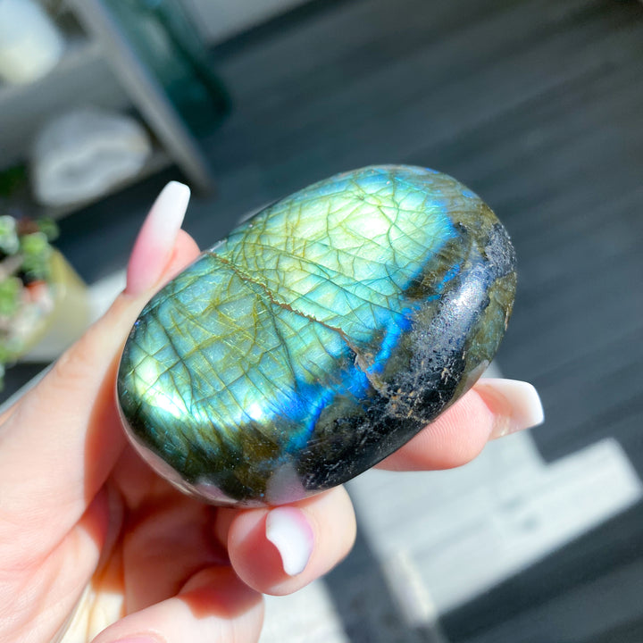 Hand holding a labradorite stone with colorful patterns
