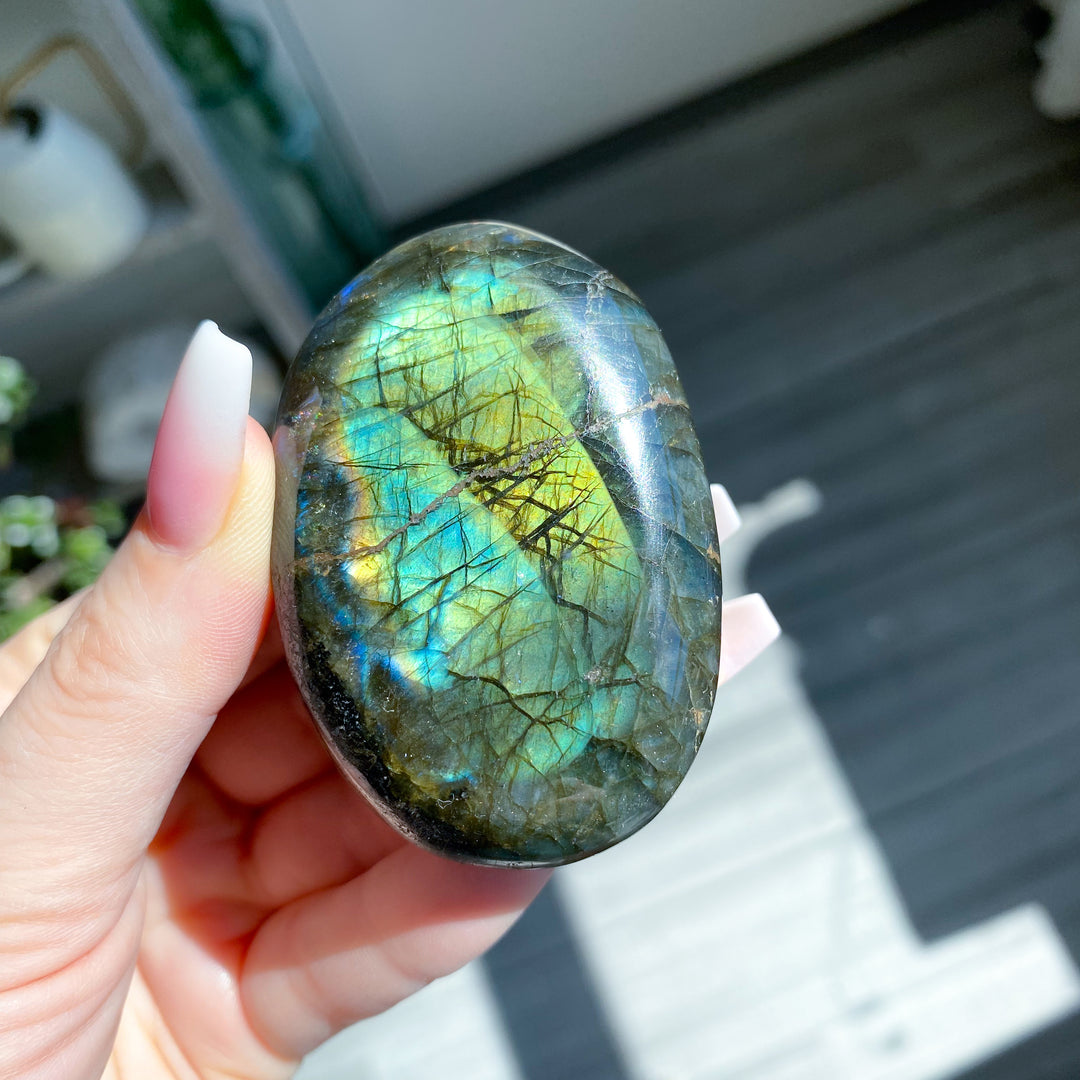 Hand holding a labradorite stone with colorful sheen