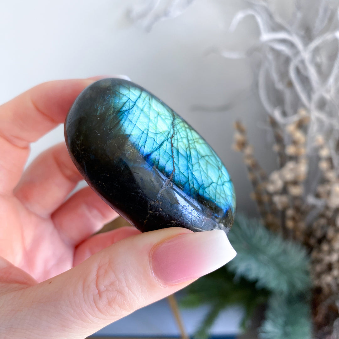 Hand holding a labradorite stone with a reflective surface