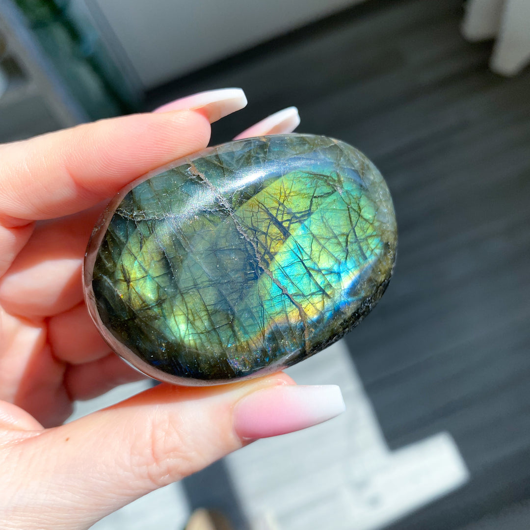 Hand holding a labradorite stone with colorful patterns