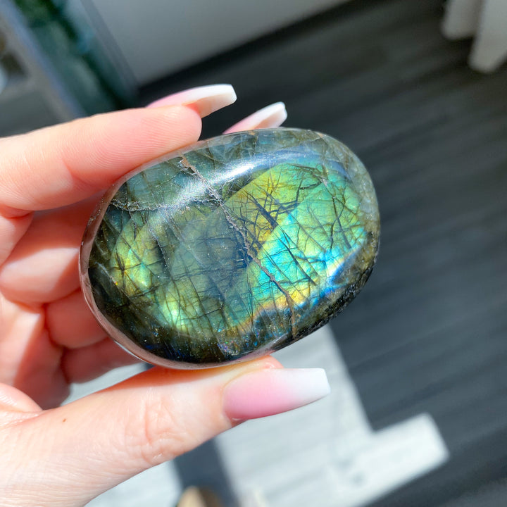 Hand holding a labradorite stone with colorful patterns
