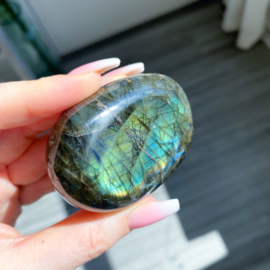 Hand holding a Labradorite stone with a blurred background