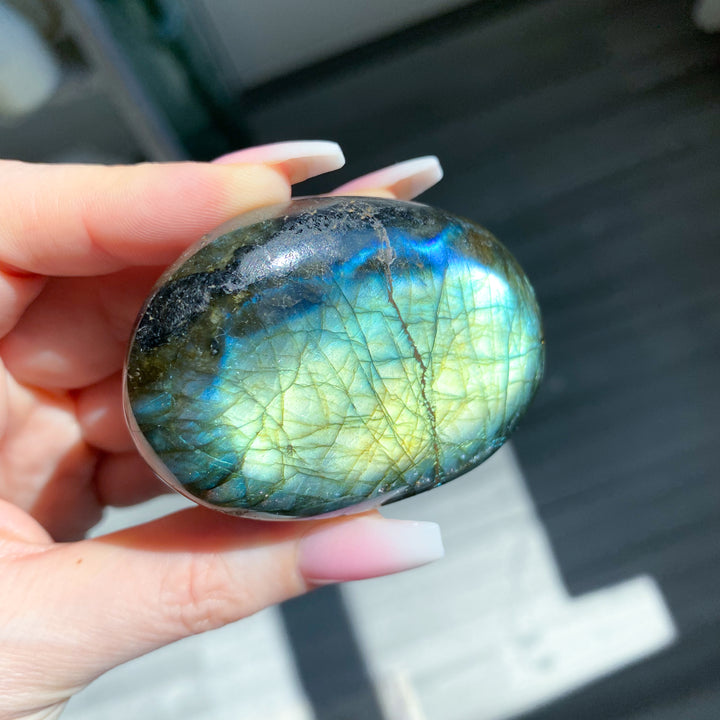 Hand holding a labradorite stone with colorful patterns