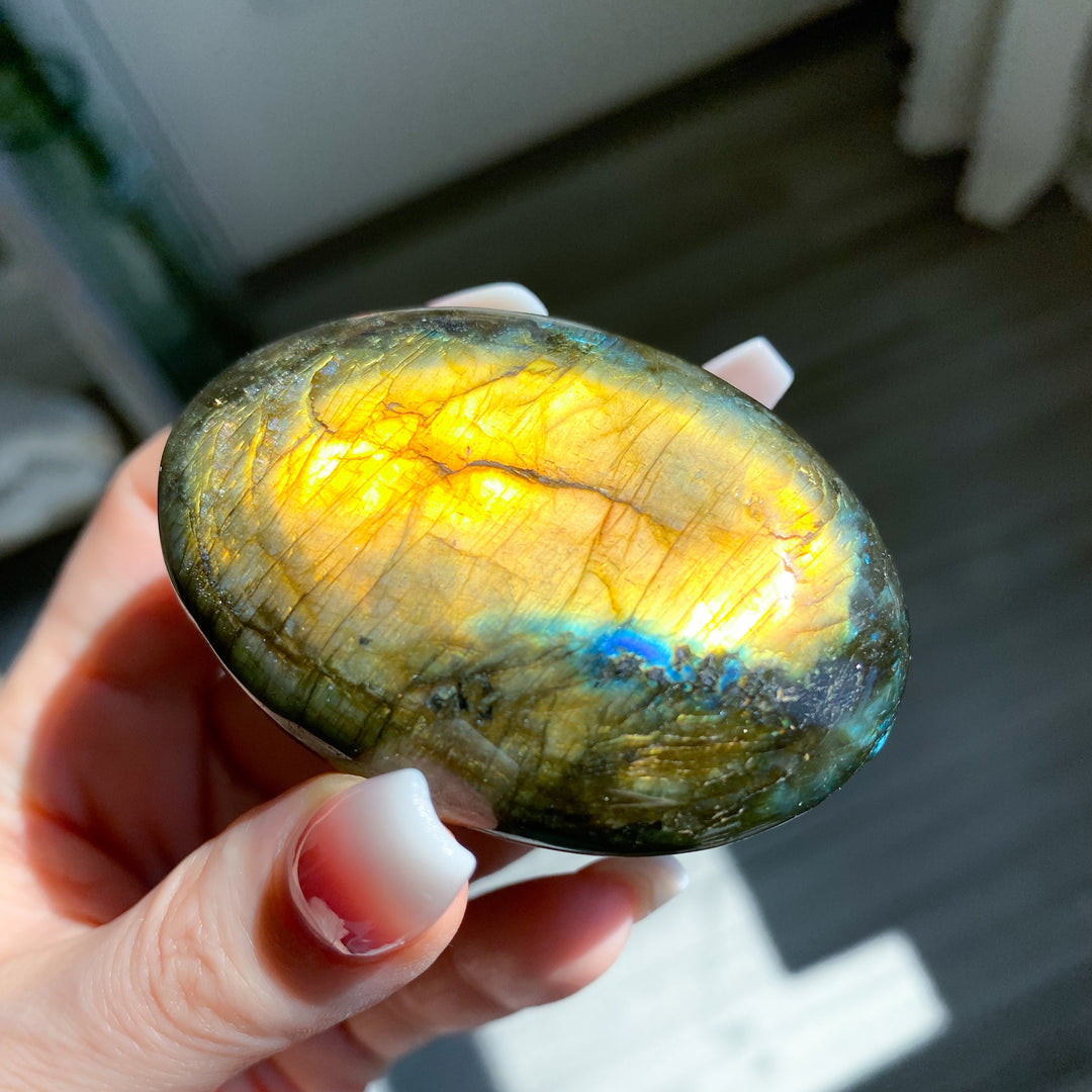 Hand holding a labradorite stone with colorful reflections