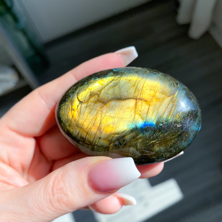 Hand holding a Labradorite stone with a reflective surface