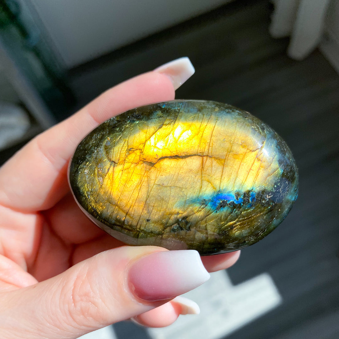 Hand holding a labradorite stone with a reflective surface