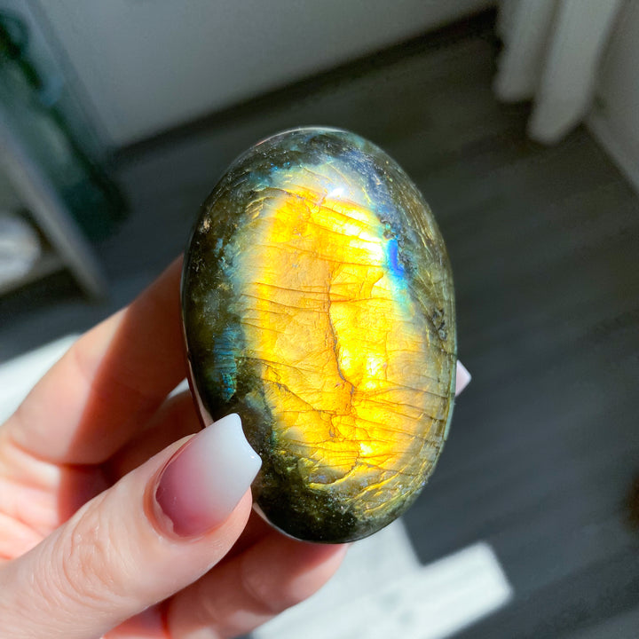 Person holding a labradorite stone with a reflective surface