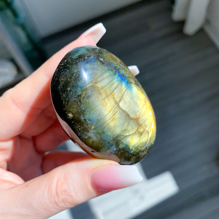 Hand holding a labradorite stone with a blurred background