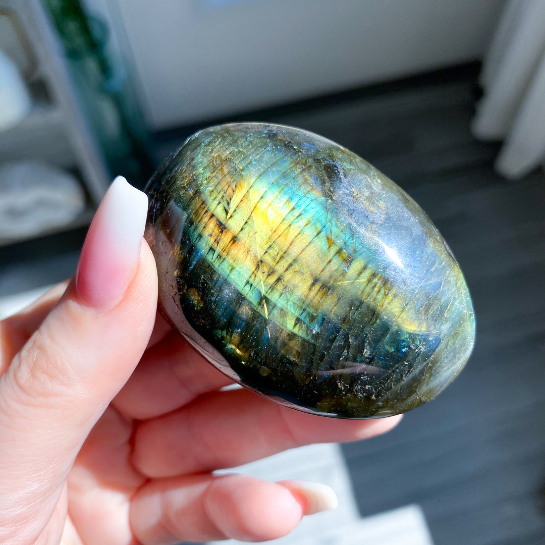 Hand holding a Labradorite stone with colorful sheen