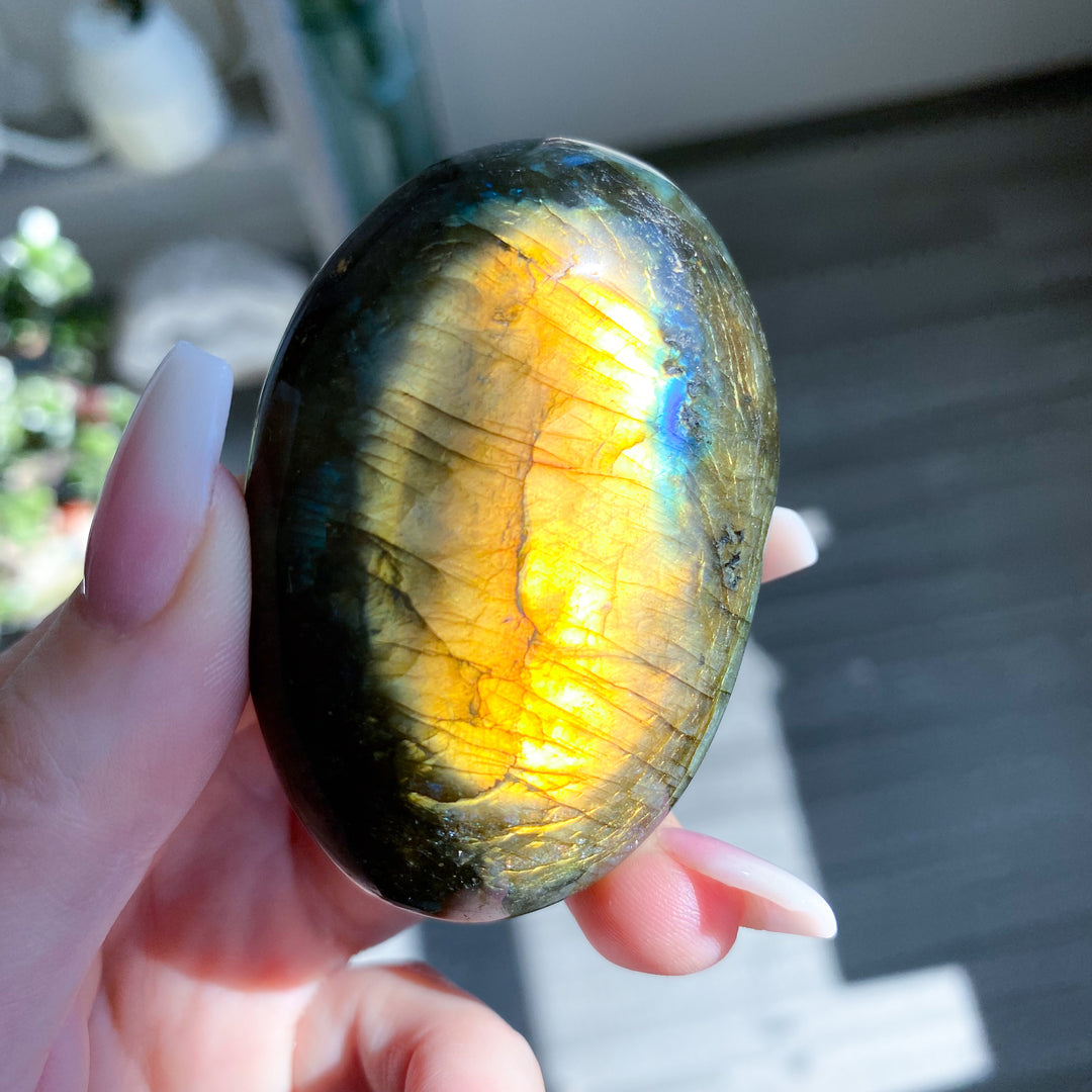Hand holding a labradorite stone with colorful reflections