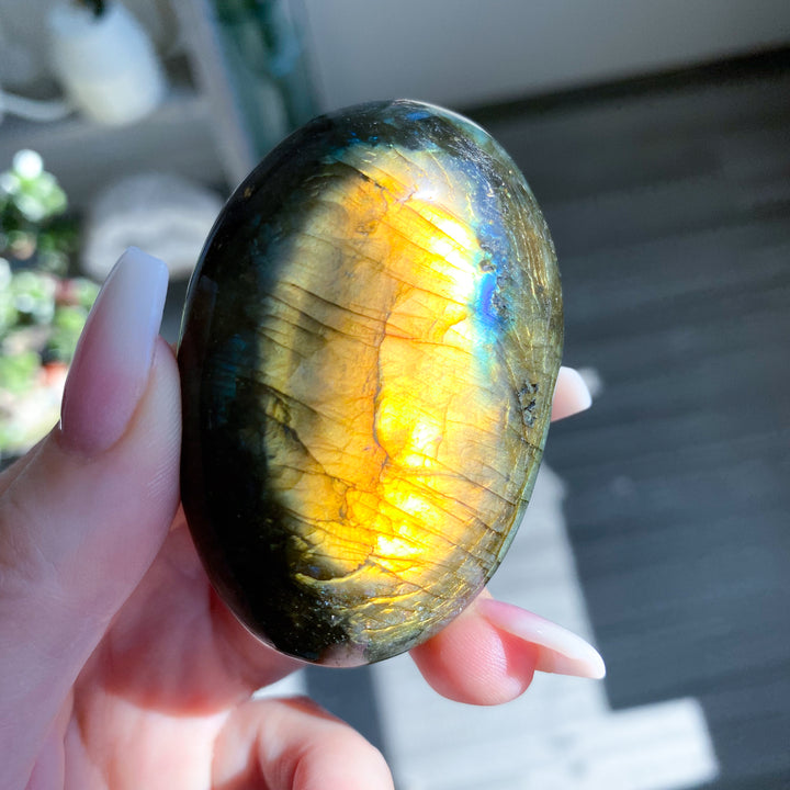 Hand holding a labradorite stone with colorful reflections