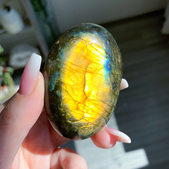 Hand holding a labradorite stone with a play of colors