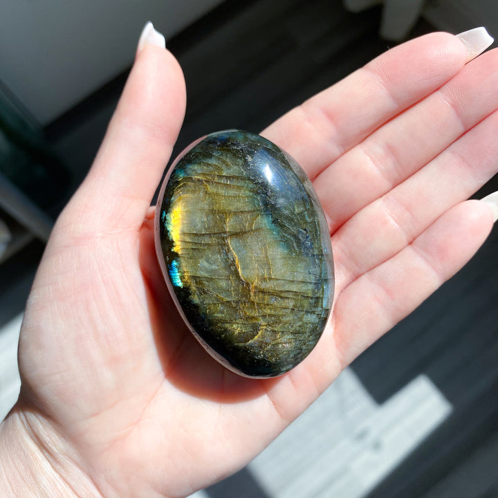 Hand holding a labradorite stone with a blurred background