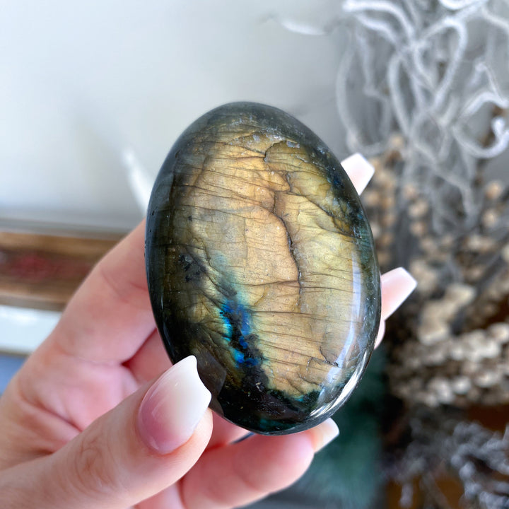 Hand holding a labradorite stone with a blurred background