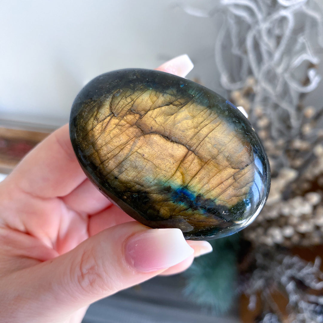 Labradorite stone held in a hand with a blurred natural background