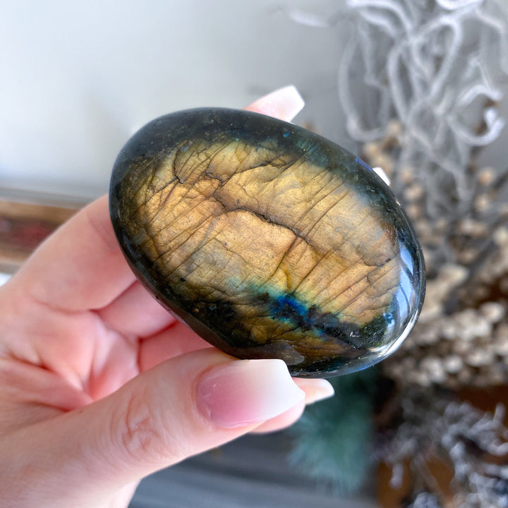 Labradorite stone held in a hand with a blurred natural background