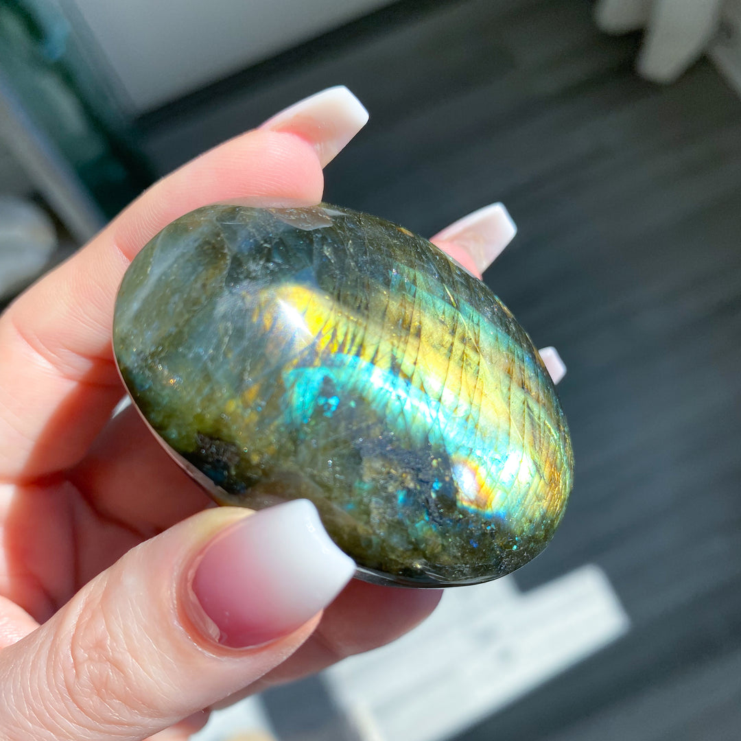 Hand holding a labradorite stone with colorful reflections