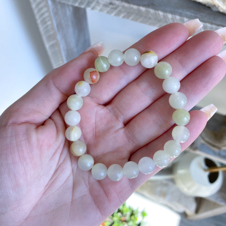 Hand holding a bracelet with white beads against a blurred background