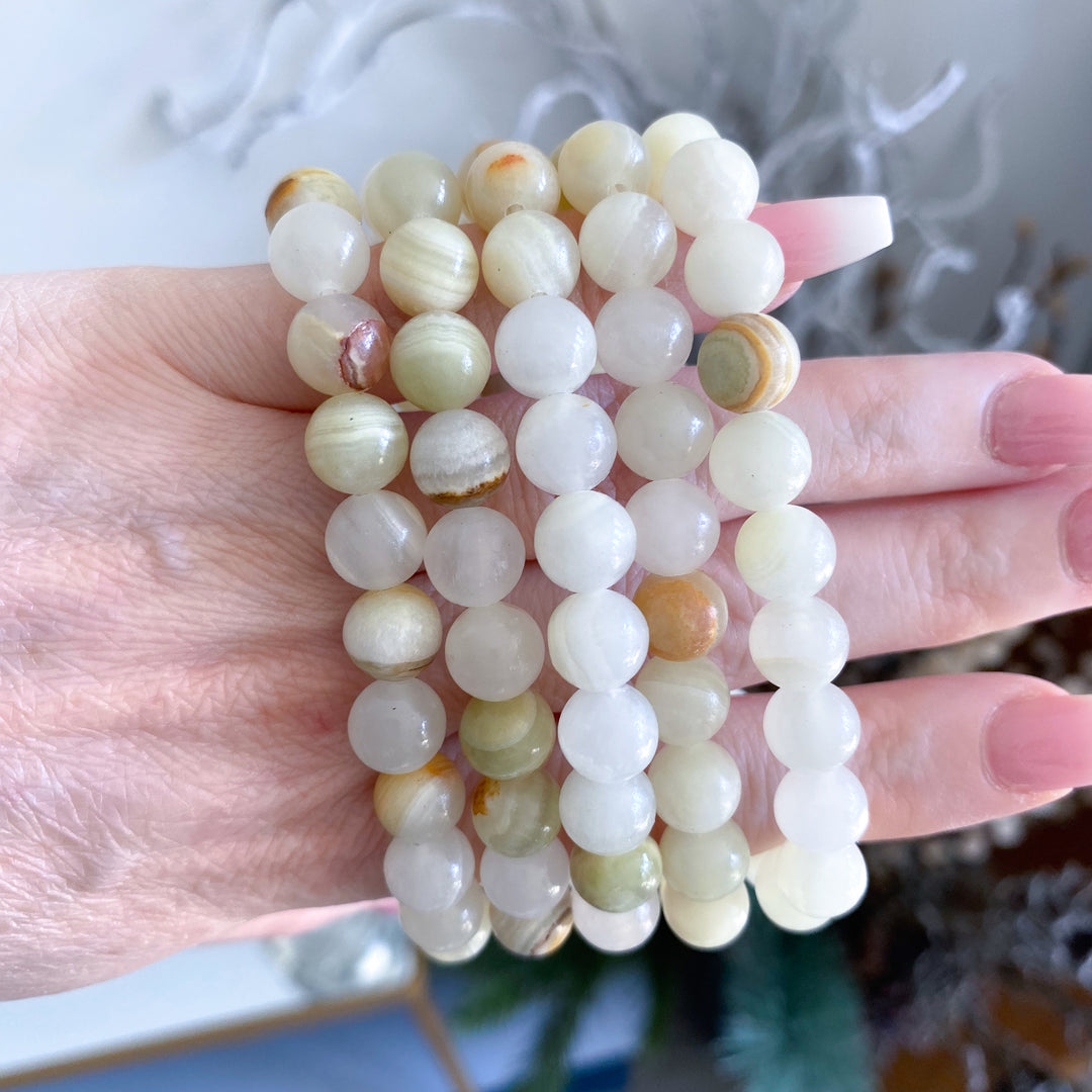 Hand holding three stacked jade bracelets with a blurred background