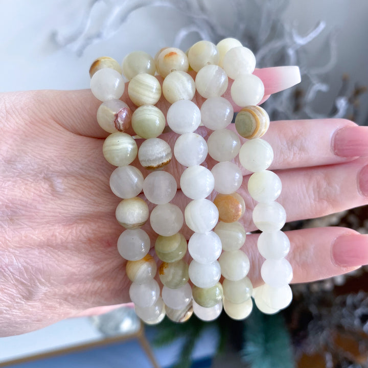 Hand holding three stacked jade bracelets with a blurred background