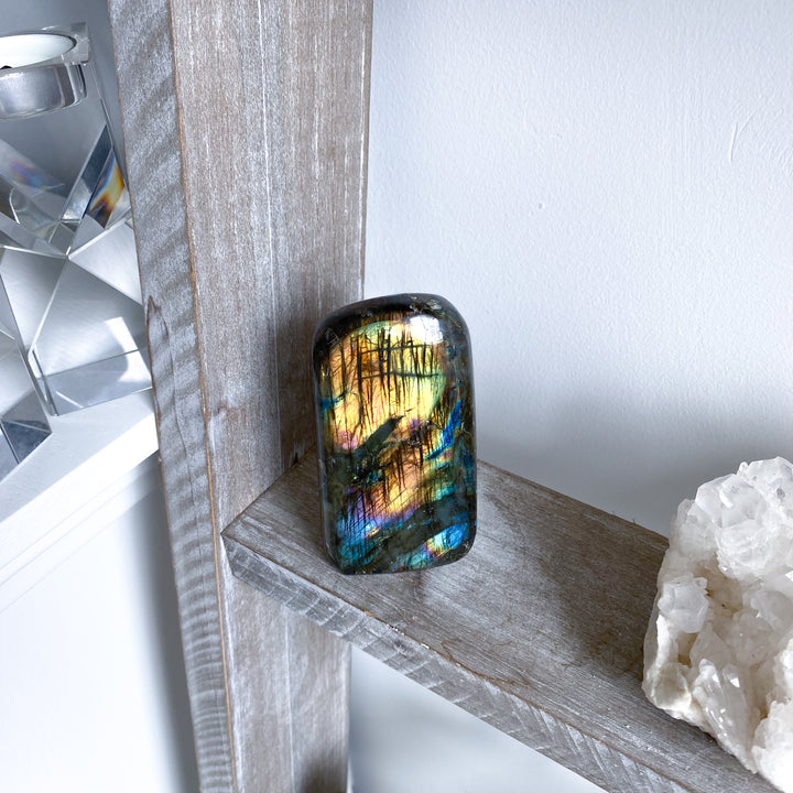 Multicolored gemstone on a wooden surface with a white background
