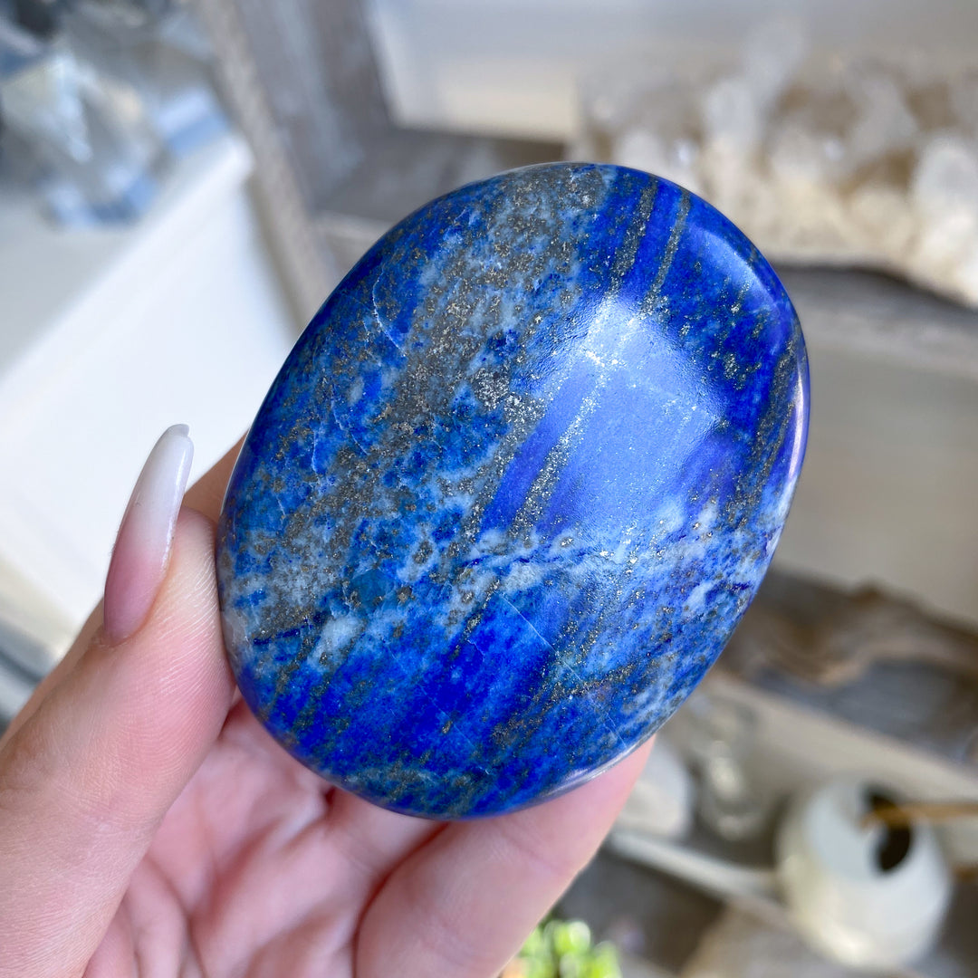 Hand holding a blue stone with a blurred indoor background