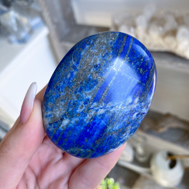 Hand holding a blue stone with a blurred indoor background