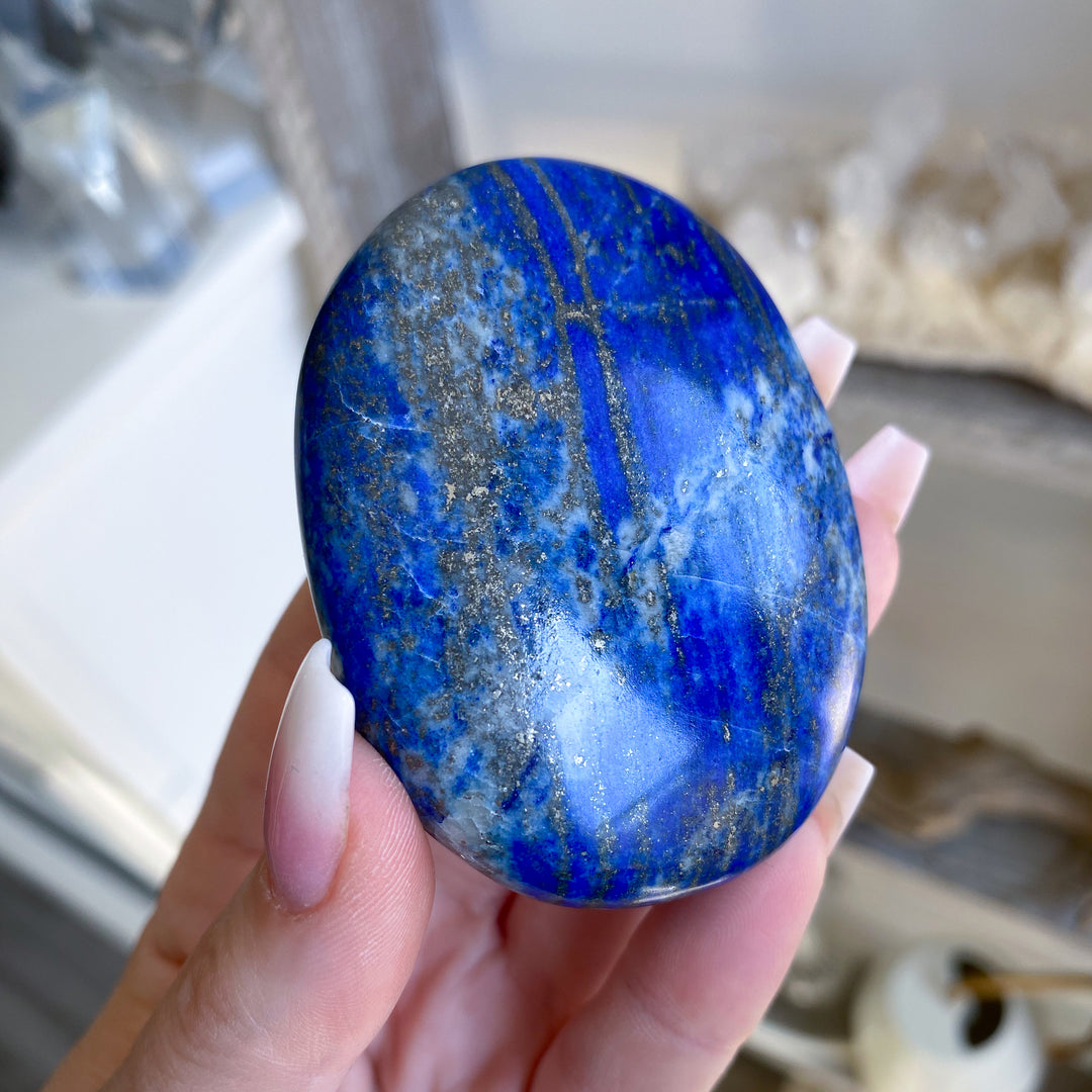 Hand holding a blue stone with white and gray patterns