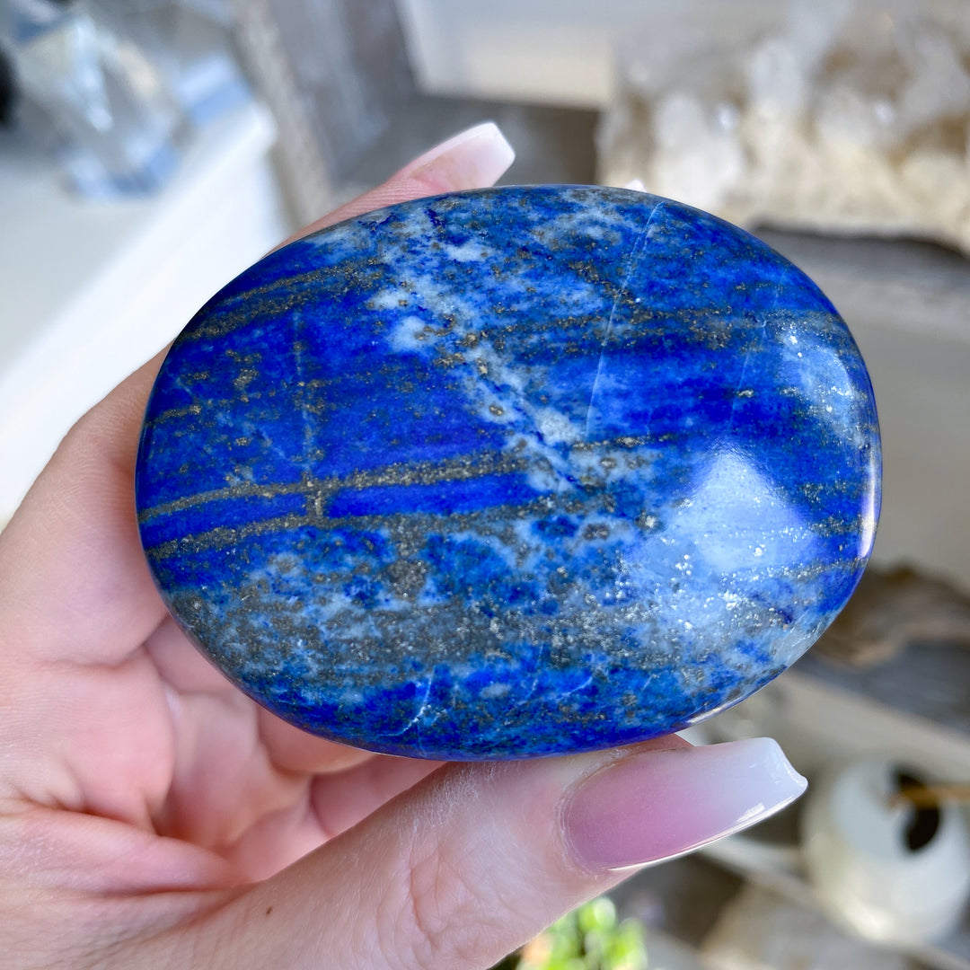 Hand holding a blue stone with a blurred background