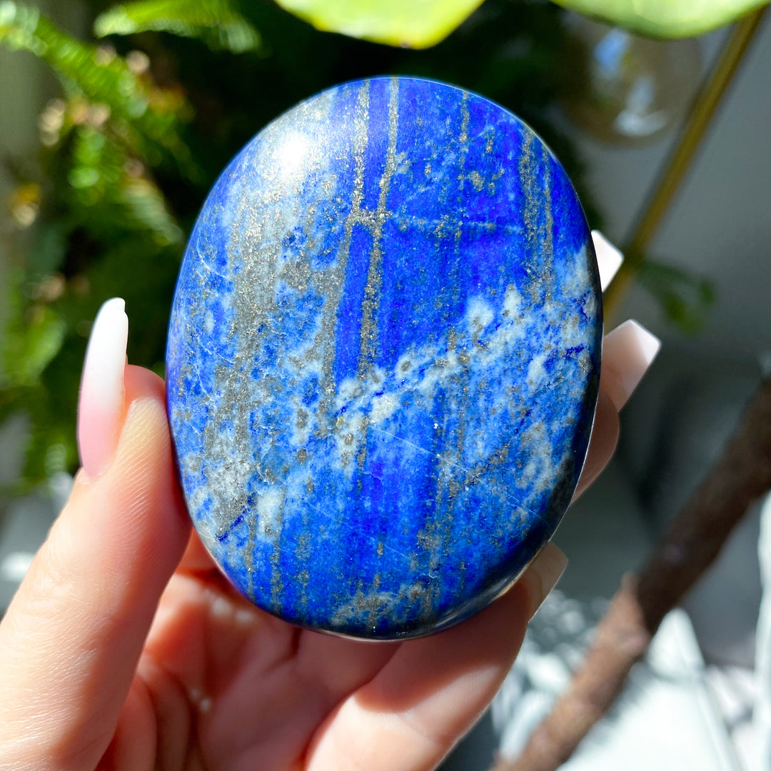 Blue stone held in a hand with a blurred natural background