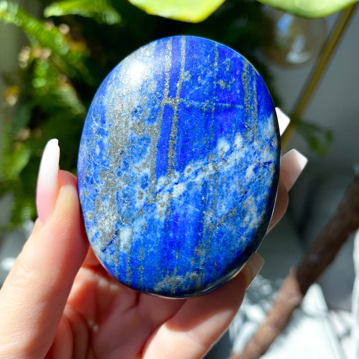Blue stone held in a hand with a blurred natural background