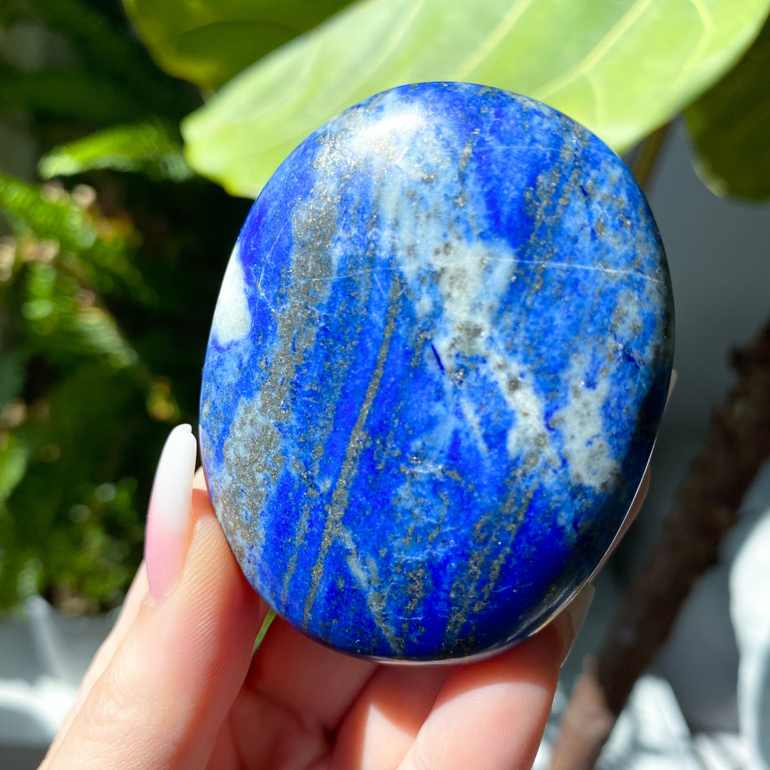 Blue stone held in a hand with a blurred natural background