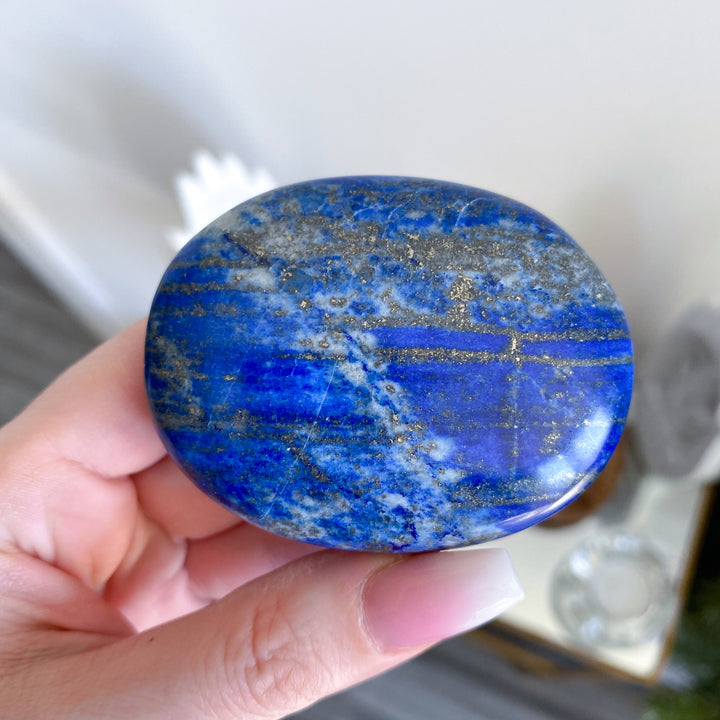 Hand holding a blue stone with a blurred background
