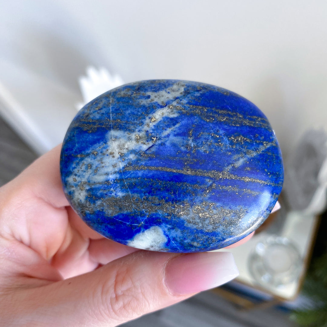 Hand holding a blue and white marbled stone with a blurred background