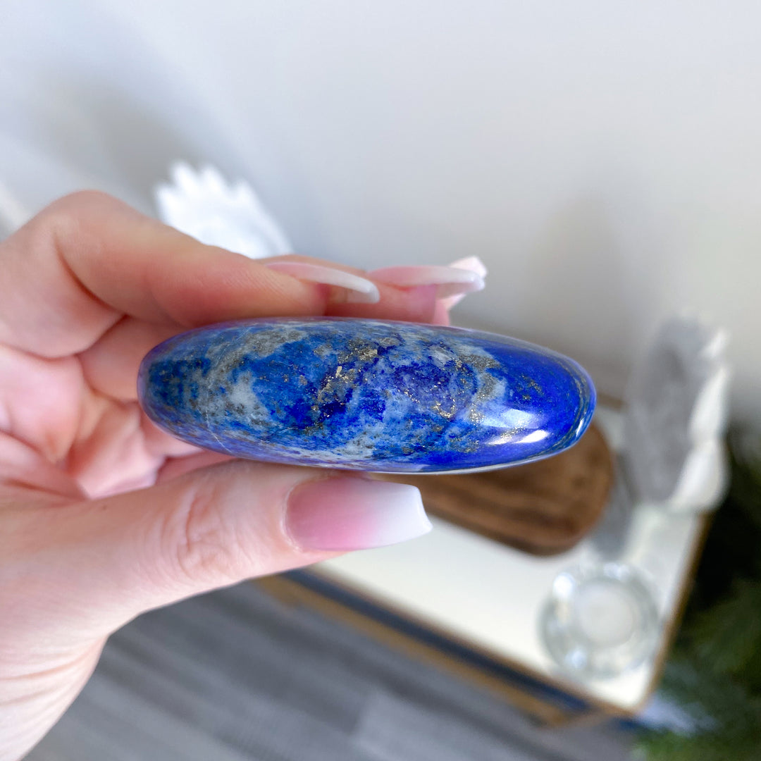 Hand holding a blue stone with a blurred background