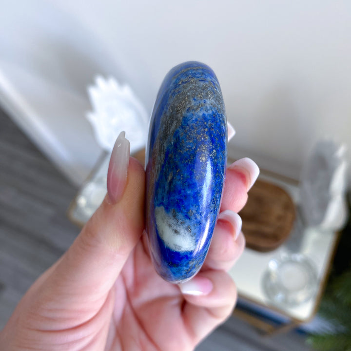 Hand holding a blue and white stone with a blurred background