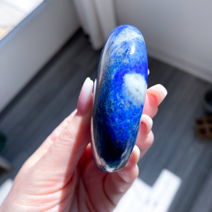 Hand holding a blue and white stone with a blurred indoor background