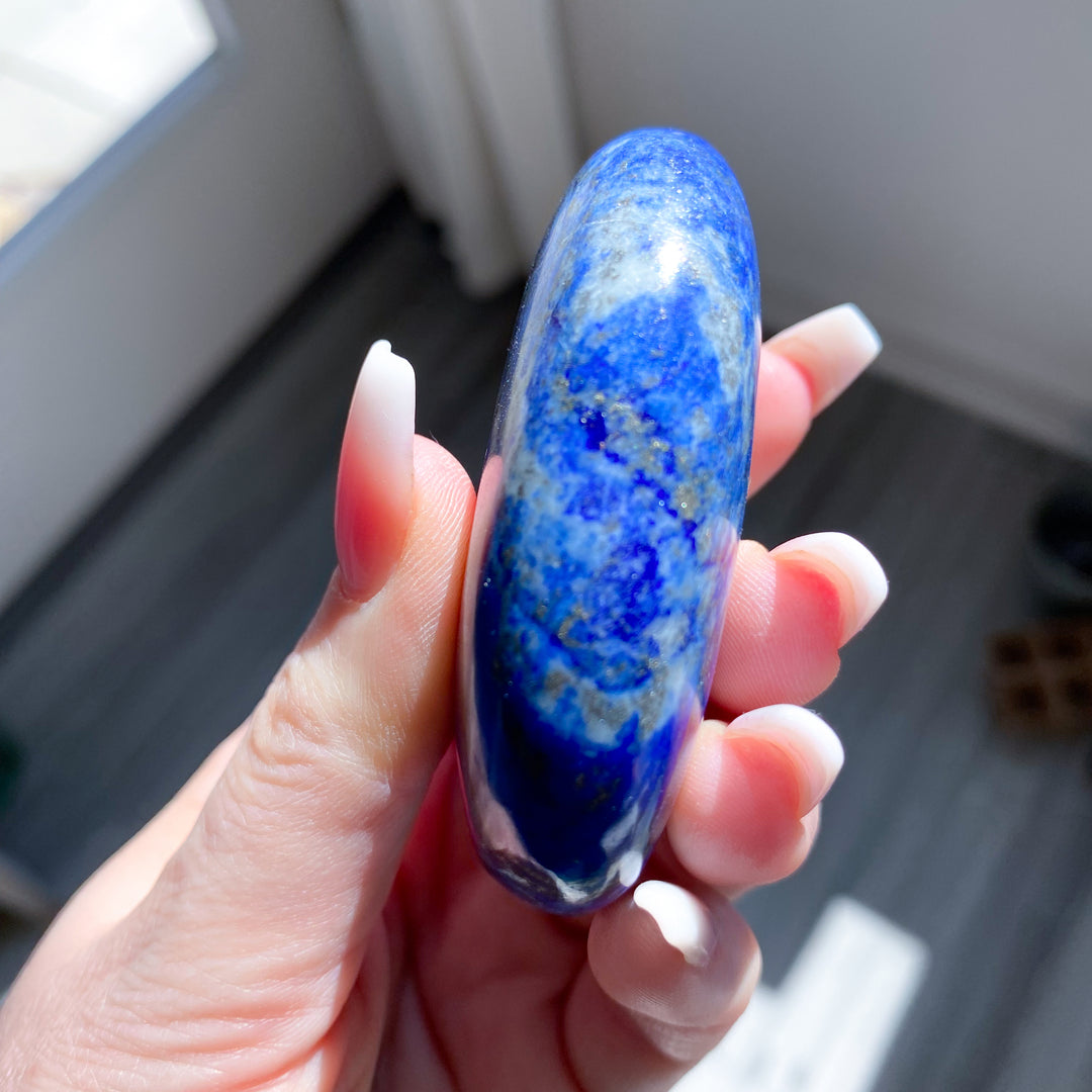Hand holding a blue gemstone with a blurred background