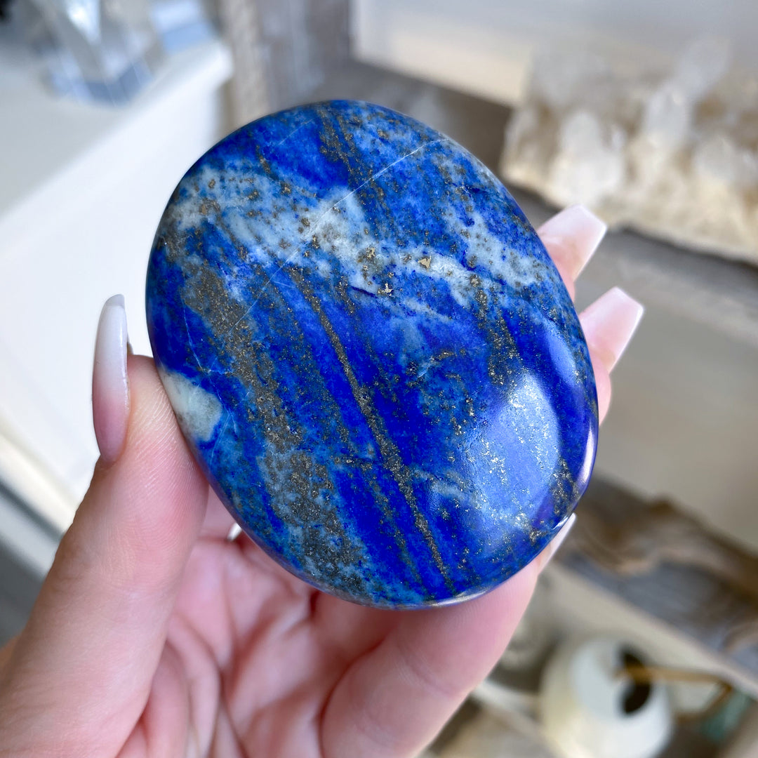 Hand holding a blue marbled stone with a blurred background